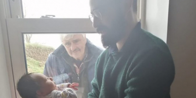 Ο παππούς κοιτάζει <br> το νεογέννητο εγγόνι <br> πίσω από το τζάμι